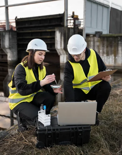 full-shot-smiley-engineers-with-laptop-outdoors